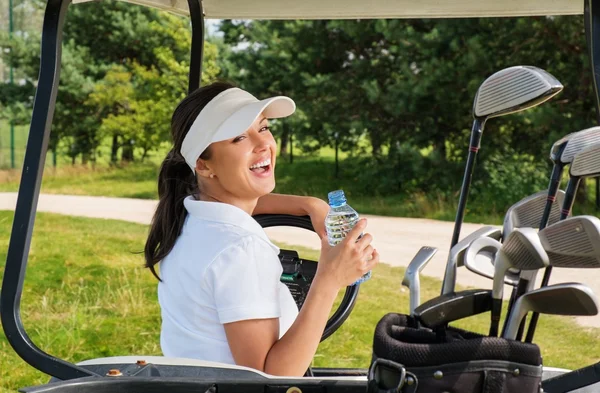 Mujer con botella de agua conduciendo carrito de golf — Foto de Stock