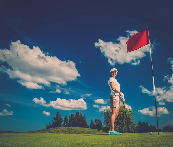 Young woman near hole with red flag on a golf club field — Stock Photo, Image