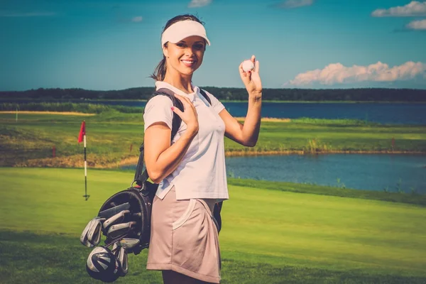 Joven mujer alegre con bolsa y pelota en un campo de golf — Foto de Stock