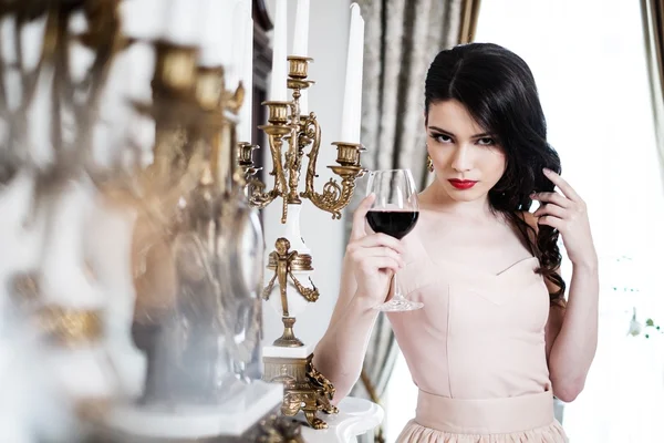 Belle jeune femme avec verre de vin rouge près de la cheminée dans l'intérieur de la maison de luxe — Photo