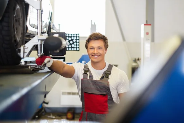 Young serviceman checking wheel alignment  in a car workshop — Stock Photo, Image