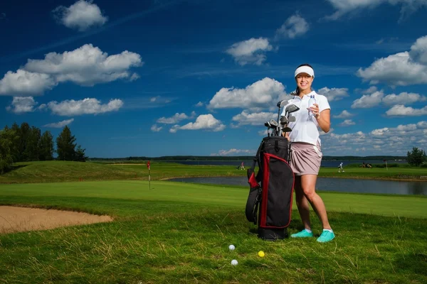 Fiatal vidám nő táska és üveg víz a golf mező — Stock Fotó
