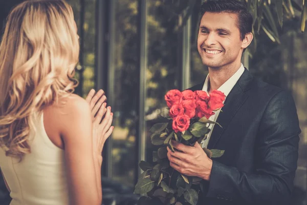 Bonito homem com um monte de rosas vermelhas namoro sua senhora — Fotografia de Stock