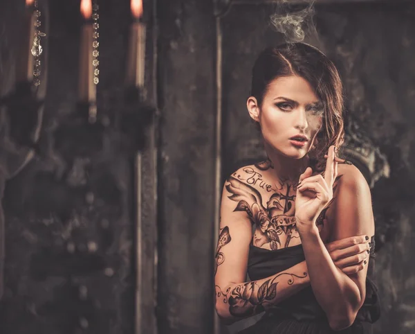 Smoking tattooed beautiful woman  in old spooky interior — Stock Photo, Image