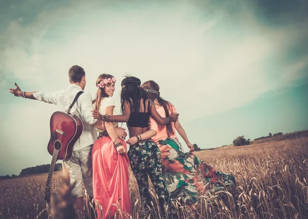 Amigos hippies multiétnicos con guitarra en un campo de trigo —  Fotos de Stock