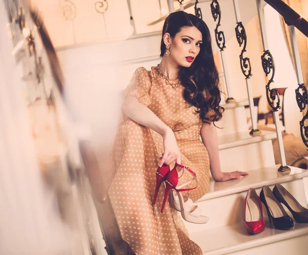 Beautiful young lady sitting on a steps in luxury house interior — Stock Photo, Image