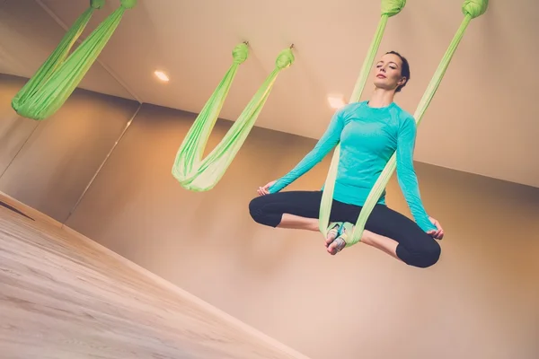 Jonge vrouw uitvoeren van anti-zwaartekracht yoga oefening — Stockfoto