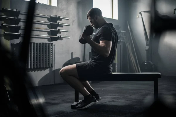 Mann trainiert Armmuskeln durch Hantelheben . Stockfoto