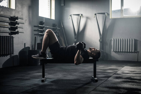Sportive Man Has Arms Workout in Dark Gym . Royalty Free Stock Photos