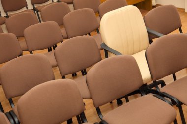 Manager chair among ordinary chairs clipart