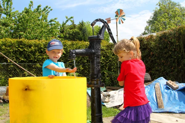 The girl and the boy at the water pump — Stock Photo, Image