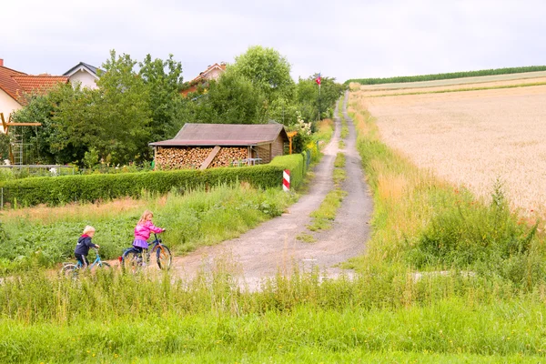 Crianças de bicicleta vão na estrada de campo — Fotografia de Stock
