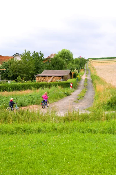 Crianças de bicicleta vão na estrada de campo — Fotografia de Stock