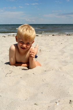 Çocuk deniz sahilde yer alır.