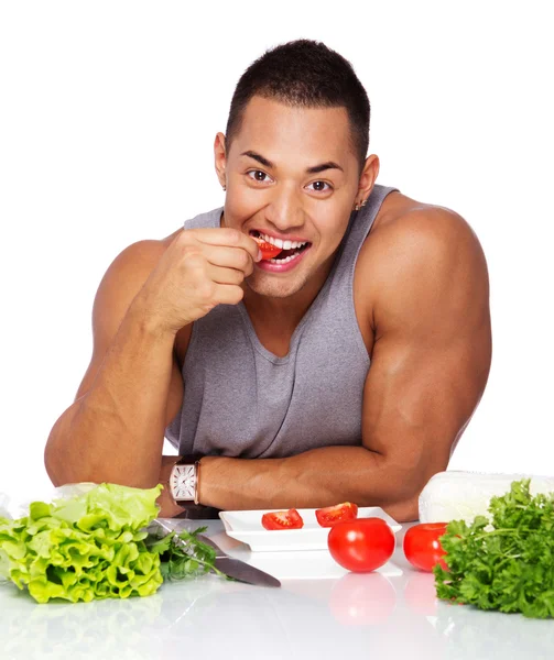 Portrait of handsome man eating tomato in studio — Stock Photo, Image