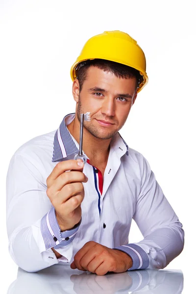Retrato de trabajador guapo posando en estudio con casco y llave — Foto de Stock