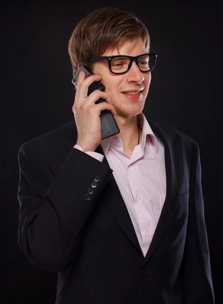 Retrato de hombre guapo posando sobre fondo negro con teléfono — Foto de Stock