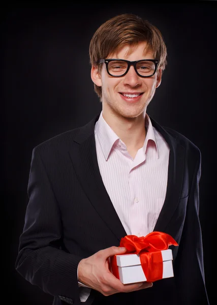 Retrato de hombre guapo posando sobre fondo negro con regalo —  Fotos de Stock