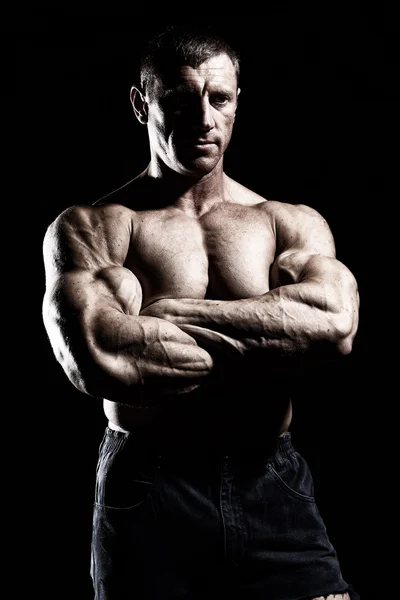 El hombre musculoso sin camisa posa con las manos cruzadas sobre el negro — Foto de Stock