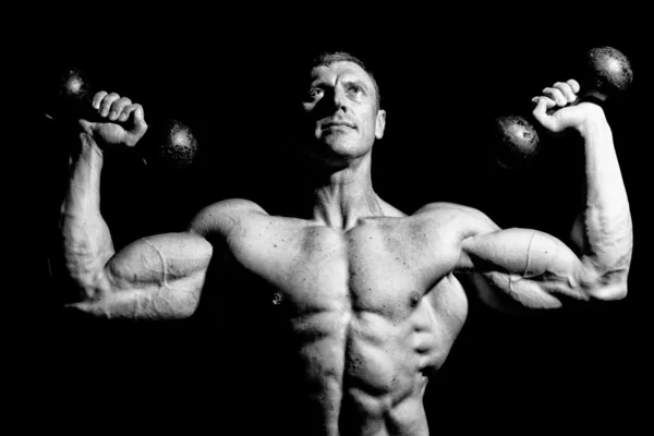 Enorme hombre está posando en estudio con pesas —  Fotos de Stock