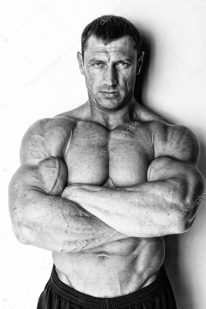 Well trained serious muscle man is posing with crossed hands