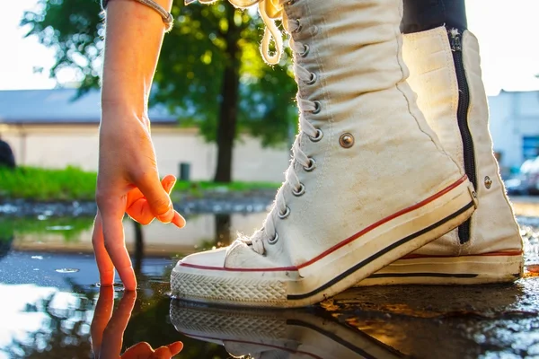 A man from fingers who is walking in puddle and white gumshoes — Stock Photo, Image