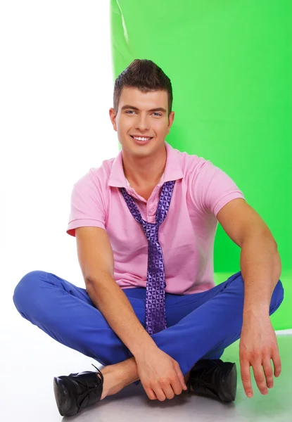 Young attractive smiling guy sitting on the floor — Stock Photo, Image