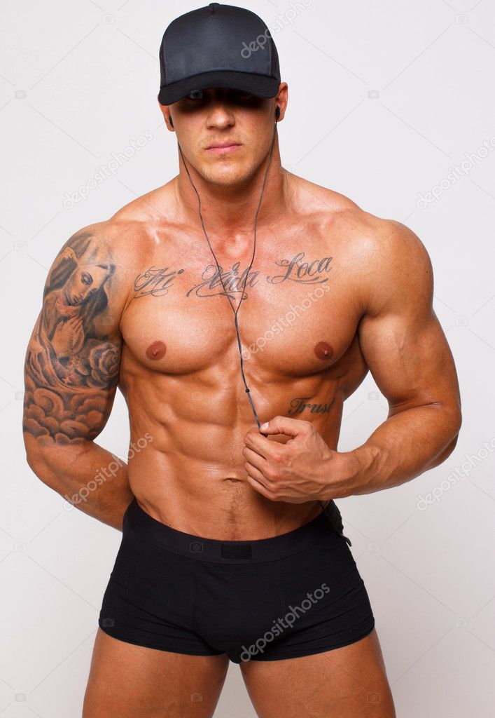 Hot guy with a well looking body is posing in pants and cap only