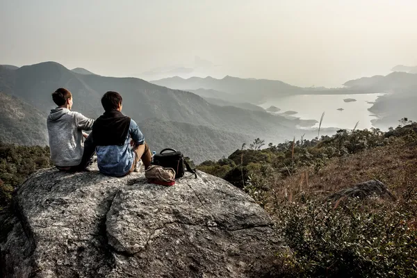 Están sentados en la montaña y mirando al horizonte — Foto de Stock