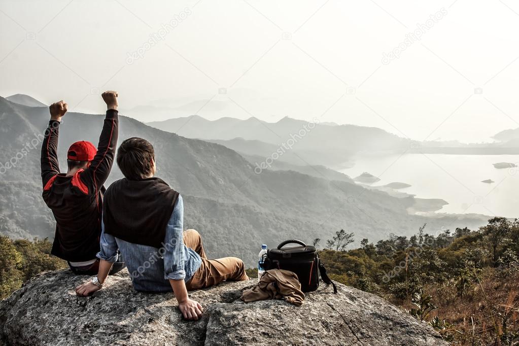 Two friends are happy that they got on top of mountain