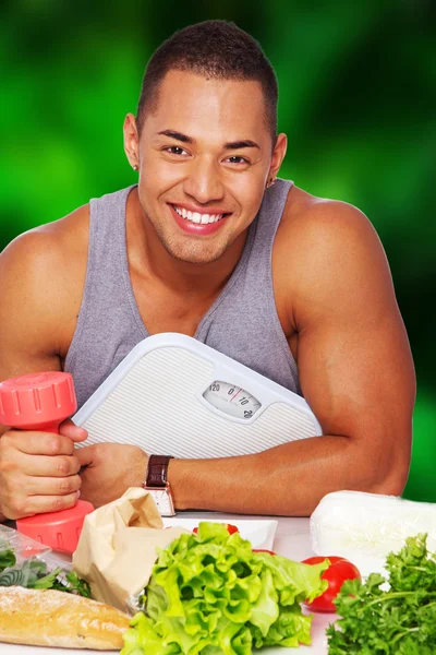 Bell'uomo sano con cibo, bilance e manubri — Foto Stock