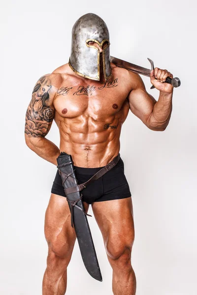 Heißer Krieger mit Helm hält Schwert in der Schulter — Stockfoto