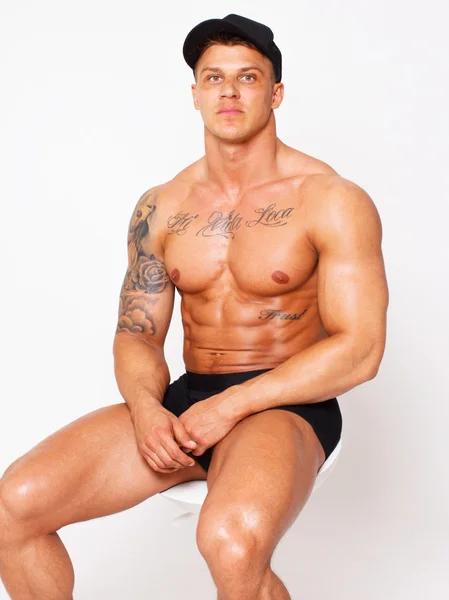 Verlegen shirtless bodybuilder zit op de stoel — Stockfoto