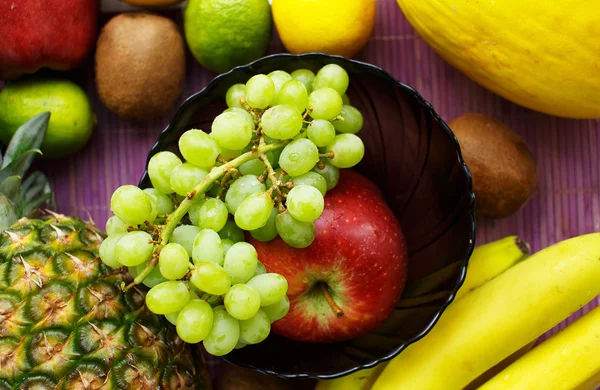 Raisin dans un bol et de nombreux autres fruits sur la table — Photo