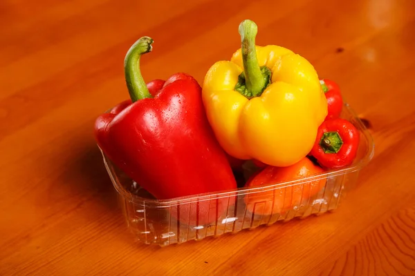 Red and yellow sweet peppers in the container — Stock Photo, Image