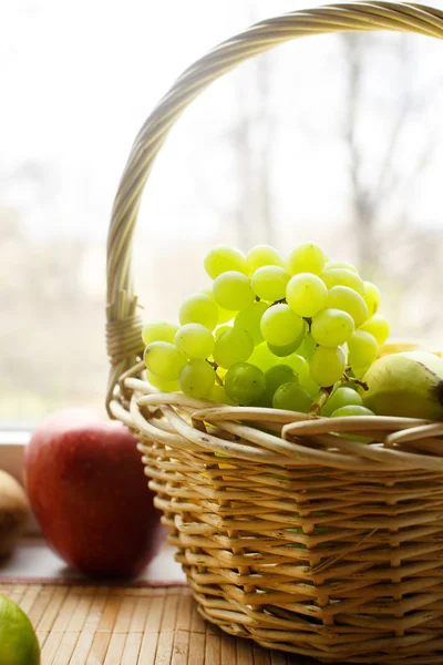 Grapes and apples near to window — Stock Photo, Image