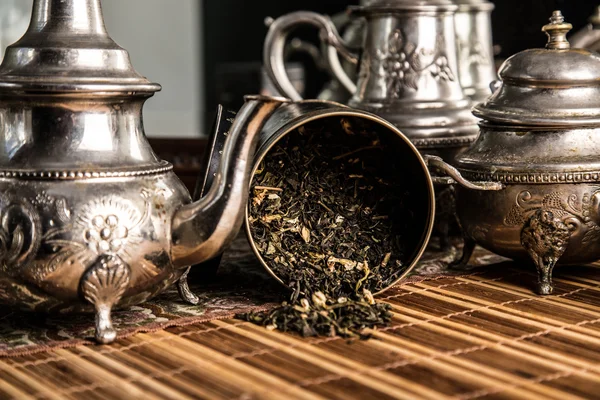 Разбросанный чай и старый чайник — стоковое фото