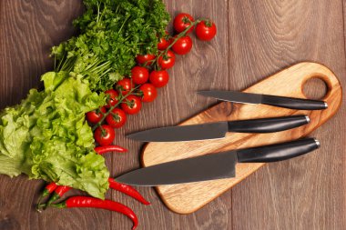 bir kesme tahtası ve sebzeler üzerinde üç bıçak