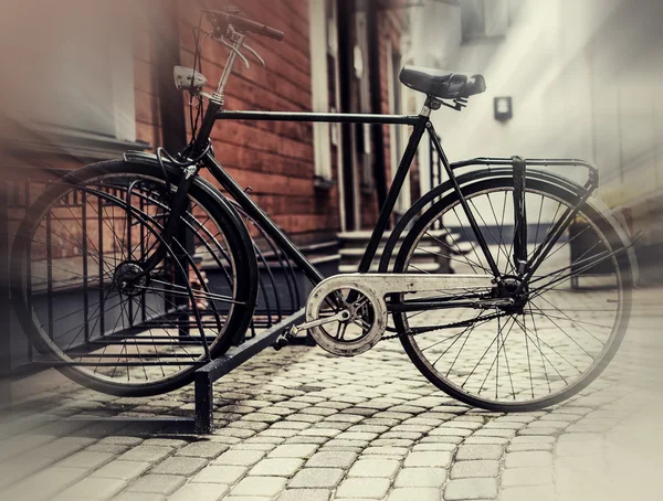 Vintage bike parked near an old wooden house on cobbled street — Stock Photo, Image