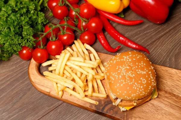 Hamburger and fries on a wooden cutting board — Stock Photo, Image