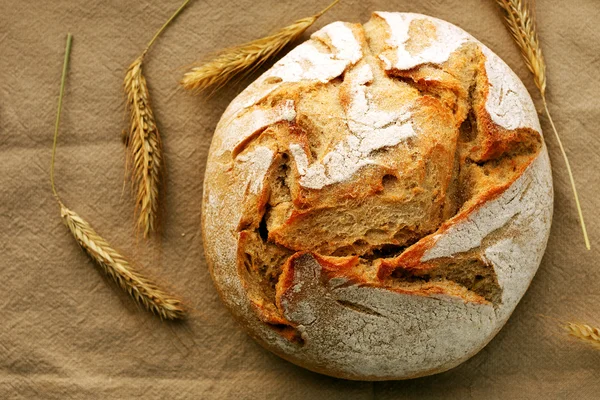 Round organic bread surrounded by wheat ears — Stock Photo, Image
