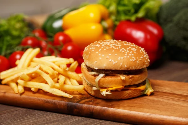 Вкусный гамбургер и чипсы на деревянной доске — стоковое фото