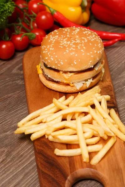 Hamburger and french fries with vegetables on wood — Stock Photo, Image