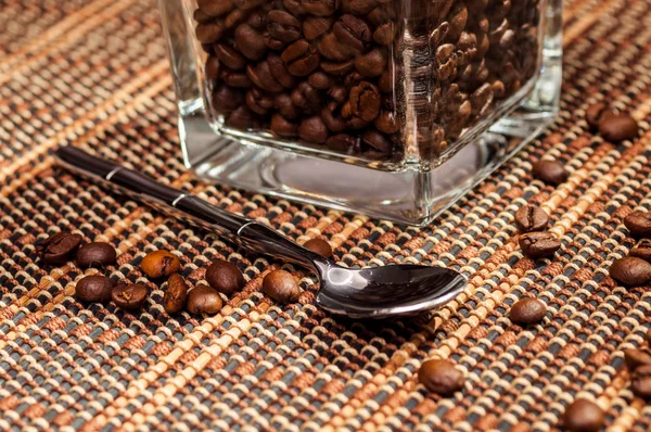 Löffel neben einem Glas Kaffeebohnen liegend — Stockfoto