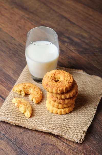 Deliziosi biscotti su un panno a sacco e un bicchiere di latte — Foto Stock