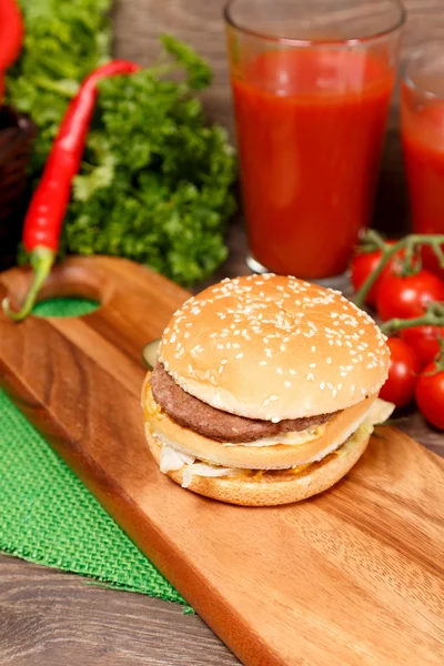 Hamburger with veggies on a wooden board — Stock Photo, Image