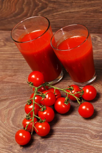 Tomatoes and two glasses on wood — Stock Photo, Image