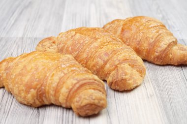 ahşap bir masa üzerinde üç ev yapımı kruvasan