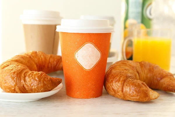 Une tasse de papier orange et deux croissants — Photo