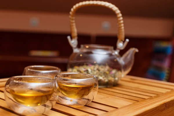 Bylinný čaj ve skleněné konvici na dřevěném prkénku — Stock fotografie